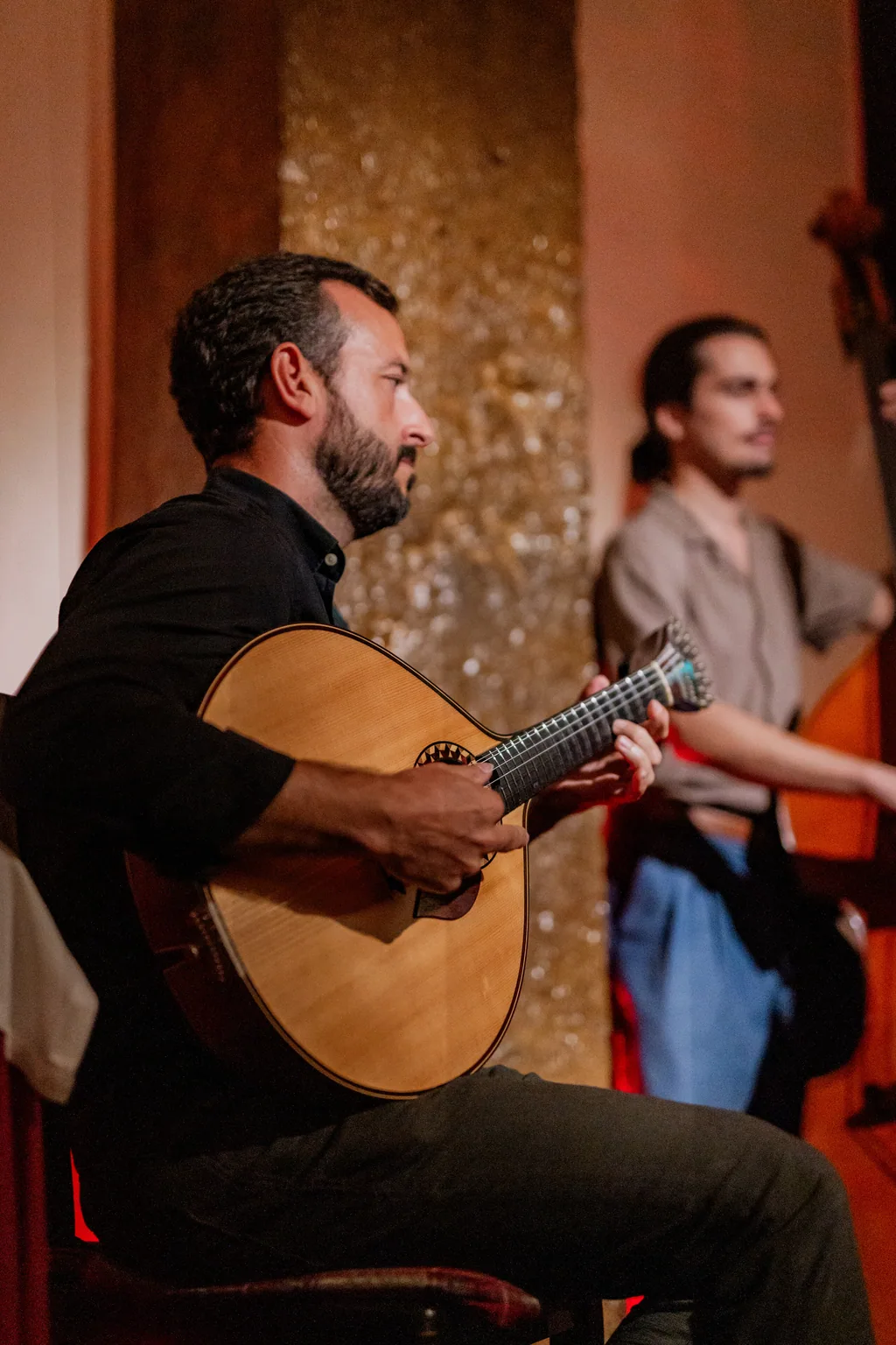 O guitarrista a tocar, o fadista de pé atrás dele