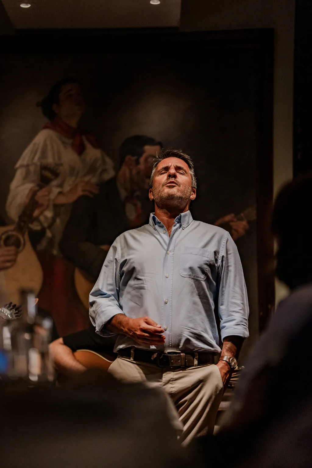 Fadista a cantar de olhos fechados diante da pintura de fadistas antigos