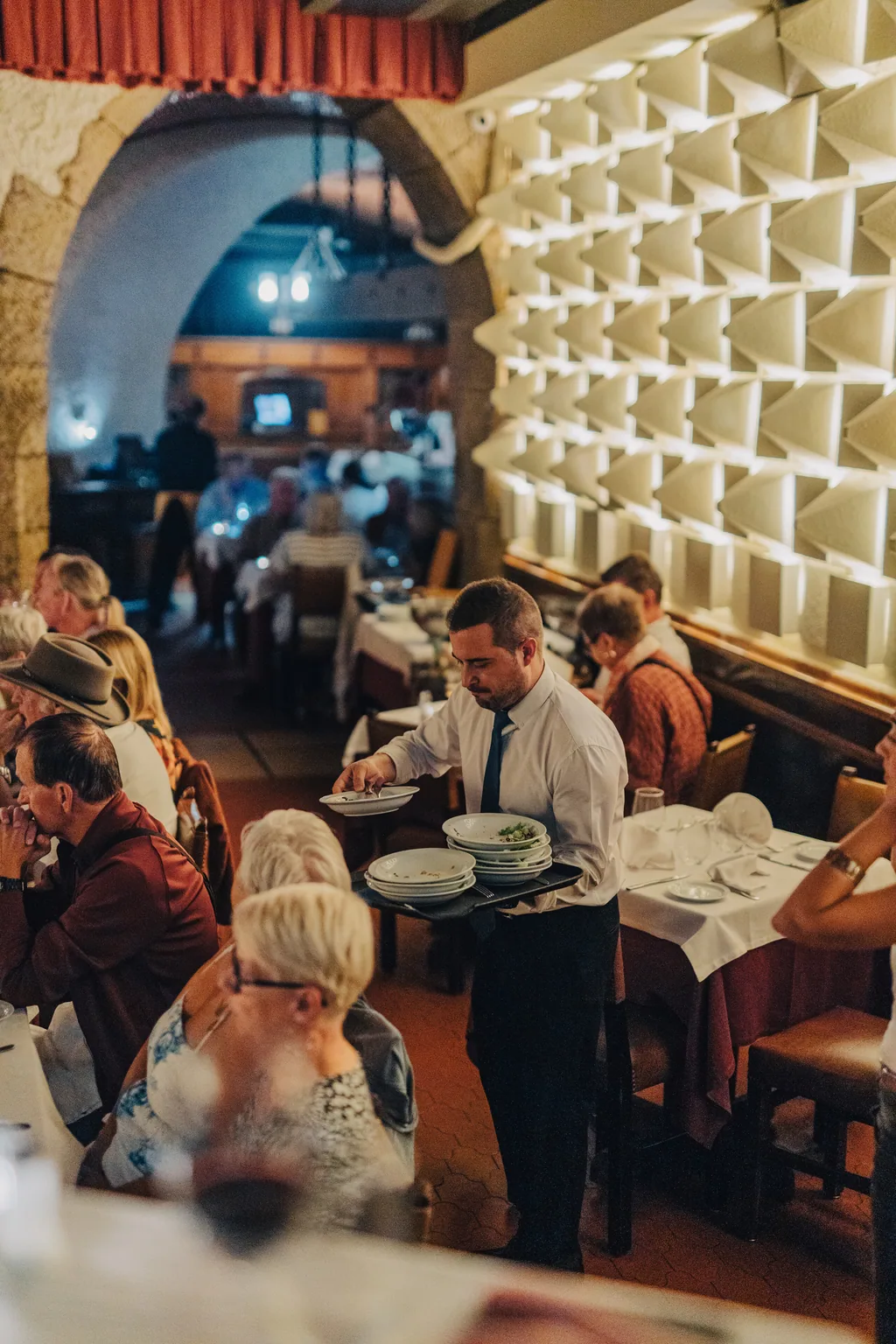 A sala cheia sob os arcos, com o serviço entre as mesas